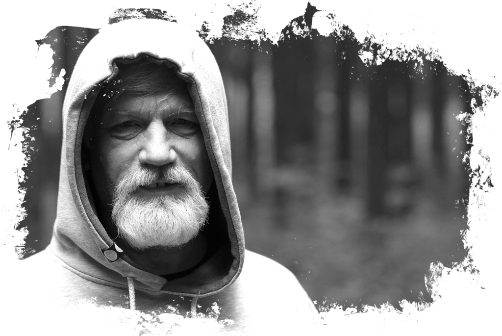Close up image of an older gentleman wearing a hoodie in the woods
